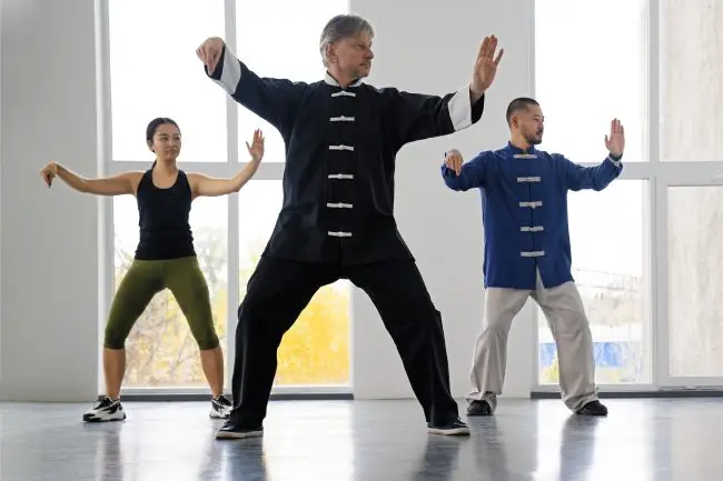 TDAH - A Atividade Física e Seu Papel no Tratamento: Lições do Tai Chi Chuan 1 Um grupo de pessoas faz ioga no parque ao pôr do sol. Estilo de vida saudável, meditação e bem-estar