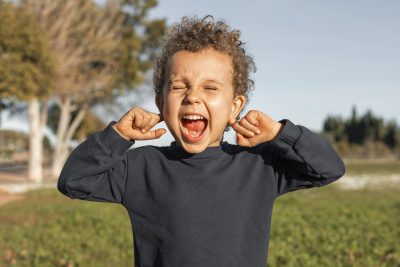 little boy outdoors covering his ears 1