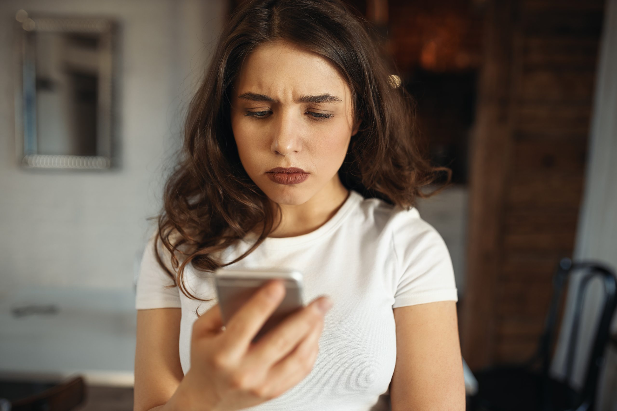 TDAH e Dependência Digital: O Que Você Precisa Saber 2 serious attractive young woman holding smart phone frowning reading sad news scaled