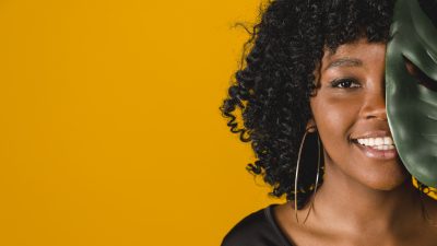 smiling young african american female with leaf colored background