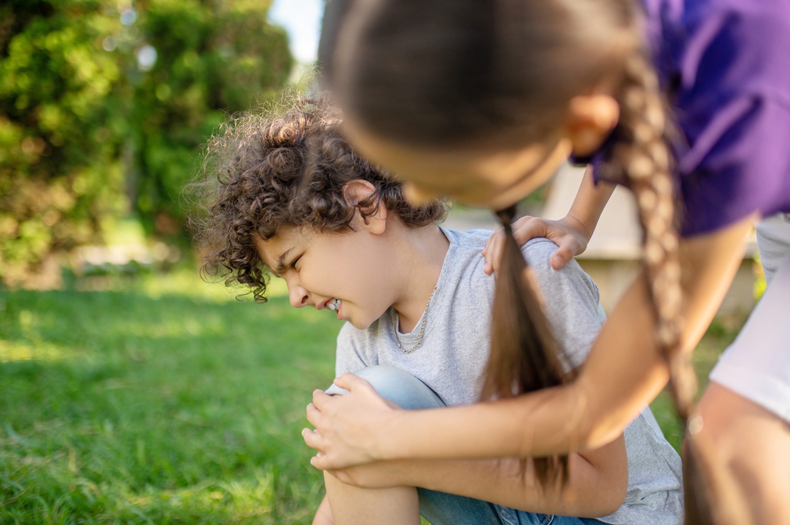 Autismo e TDAH: O Papel das Funções Executivas na Infância 2 dark haired girl leaning young caucasian boy suffering from knee pain after fall down scaled