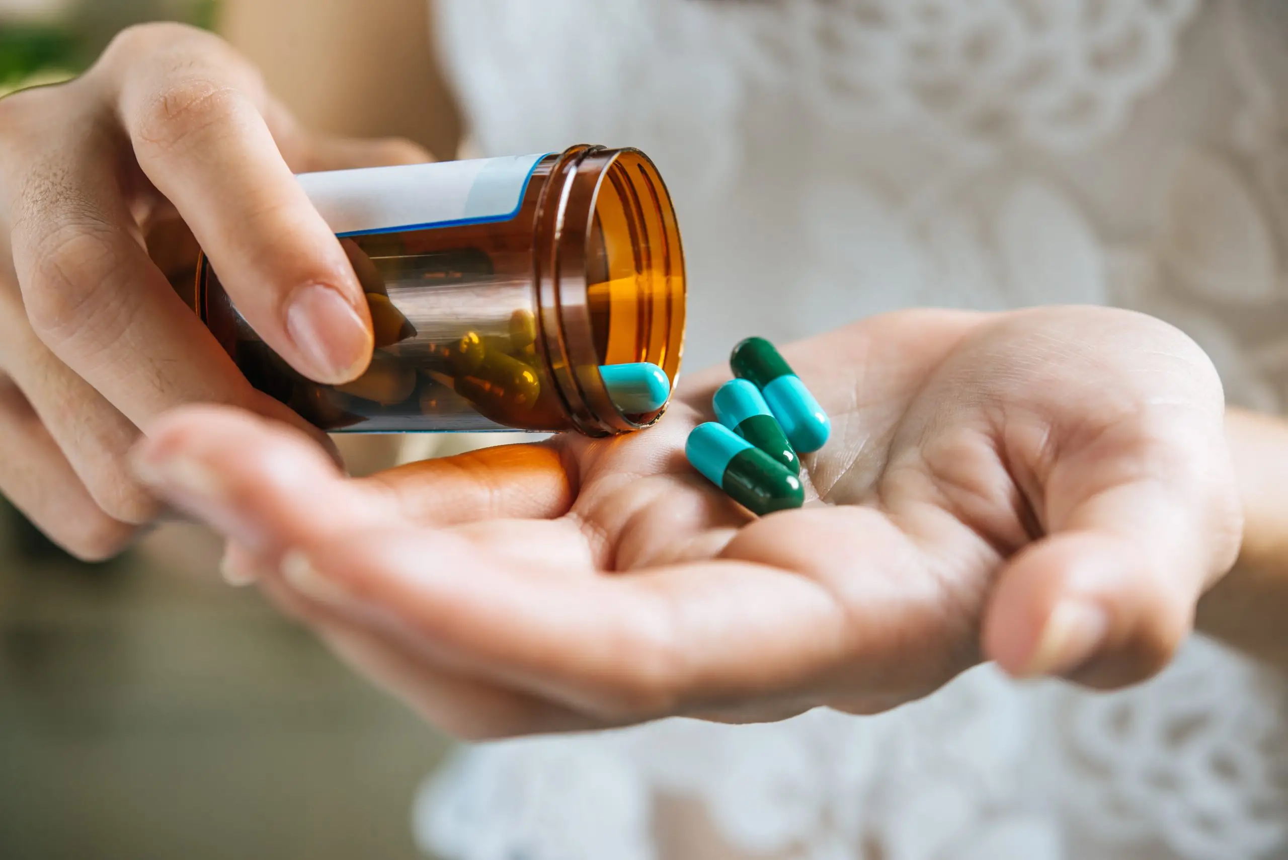 woman s hand pours medicine pills out bottle scaled