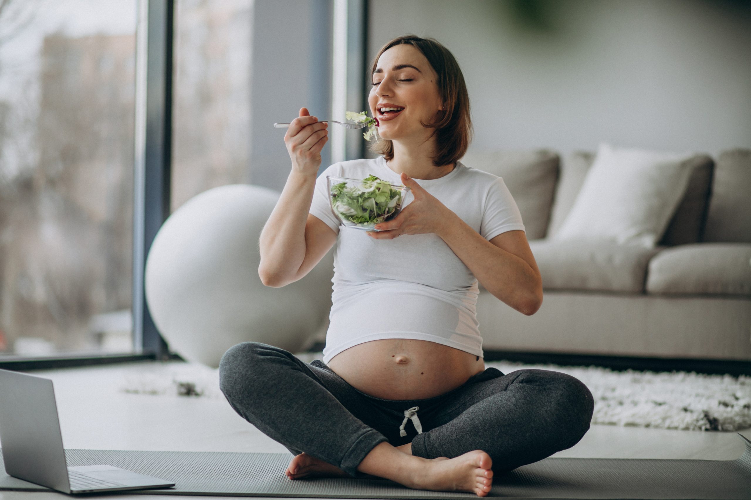 young pregnant woman eating salad home scaled